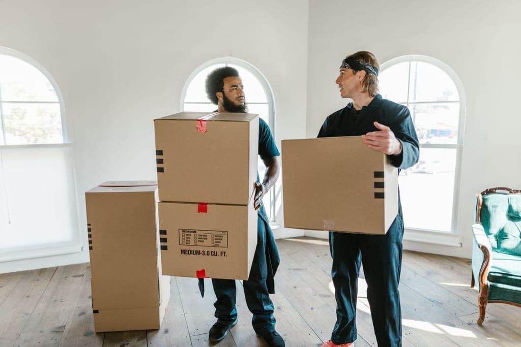 Crew carrying moving boxes out of a bright, empty room during a cleanout