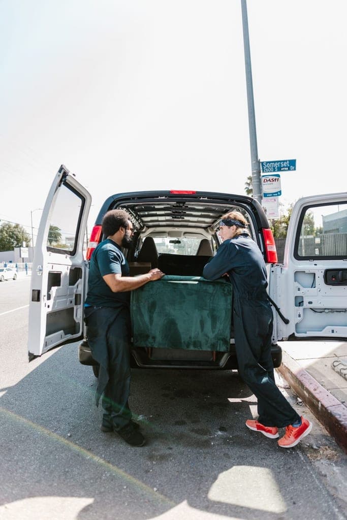 Two-person crew loading a sofa into the back of a van